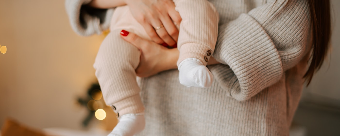 Una madre sostiene a su bebé en brazos, en luz cálida