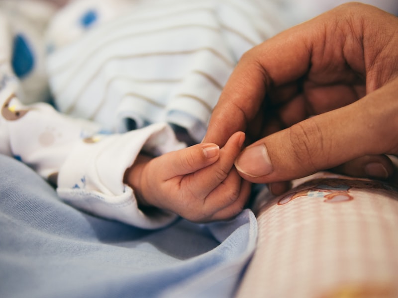 La mano de un bebé recién nacido agarra el dedo de su madre